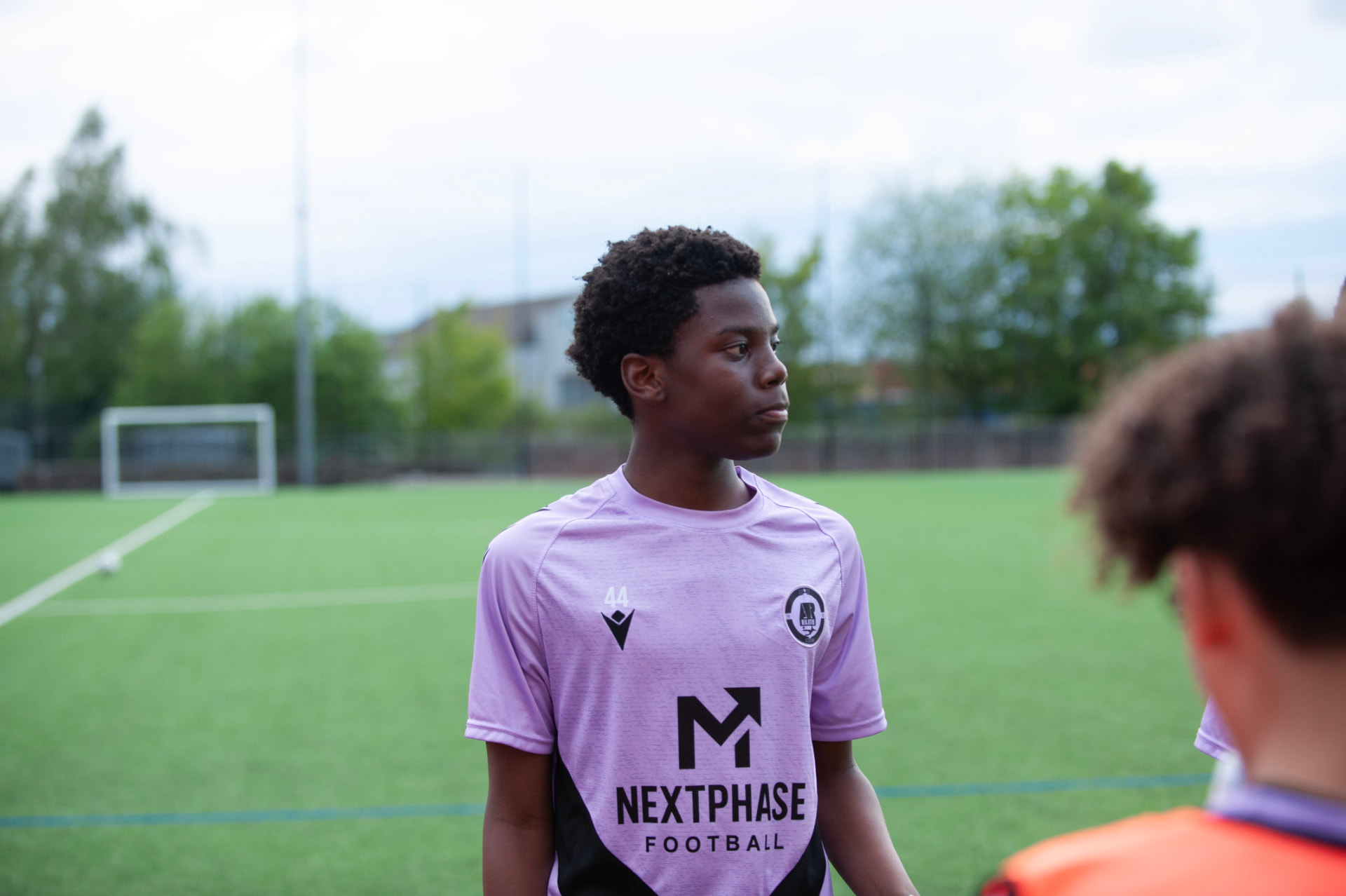 A Next Phase Football player in branded training kit focused during a session on a grass pitch.